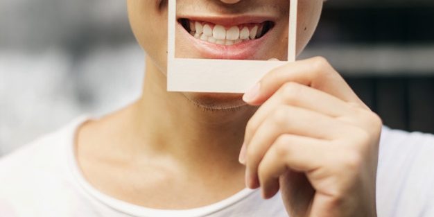Asian Guy Holding Photo Frame Smiling Smile Makeover Best Dental Implants in Hyderabad